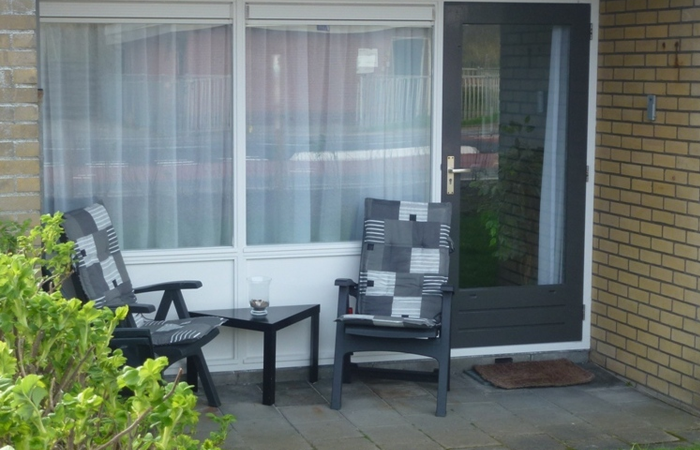 Foto Terrasse mit Tisch und zwei Stühlen vor der Terrassentür und dem Femster zum Wohnzimmer